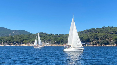 Veleros en el océano con montañas al fondo.